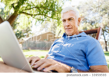 Senior man with notebook sitting in the park Senior man with notebook sitting in the park 33959593
