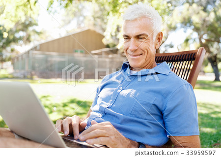 Senior man with notebook sitting in the park 33959597