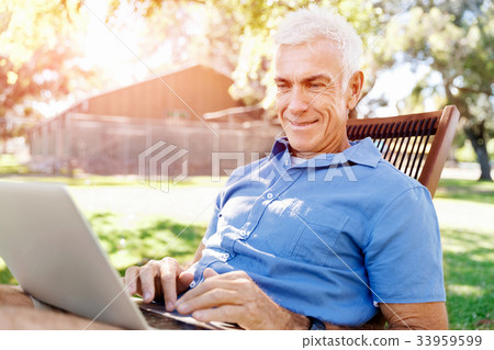Senior man with notebook sitting in the park Senior man with notebook sitting in the park 33959599