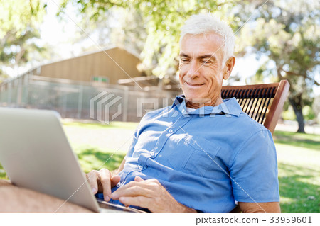 Senior man with notebook sitting in the park Senior man with notebook sitting in the park 33959601