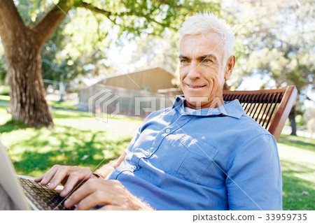Senior man with notebook sitting in the park Senior man with notebook sitting in the park 33959735