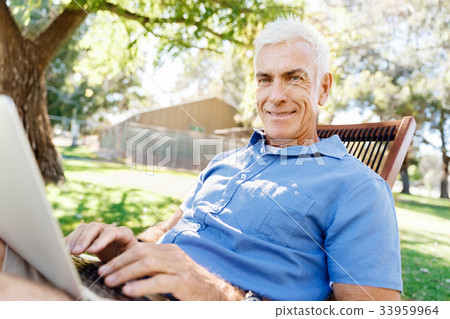 Senior man with notebook sitting in the park 33959964