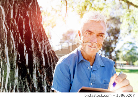 Senior man sittingin park while reading book Senior man sittingin park while reading book 33960207