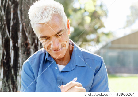 Senior man sittingin park while reading book 33960264
