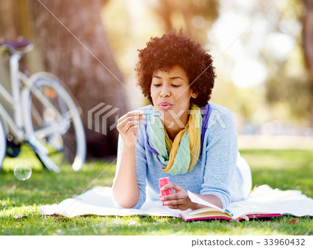 Beautiful woman blowing bubbles in park Beautiful woman blowing bubbles in park 33960432