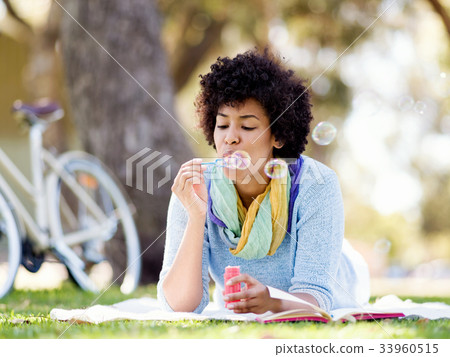 Beautiful woman blowing bubbles in park 33960515