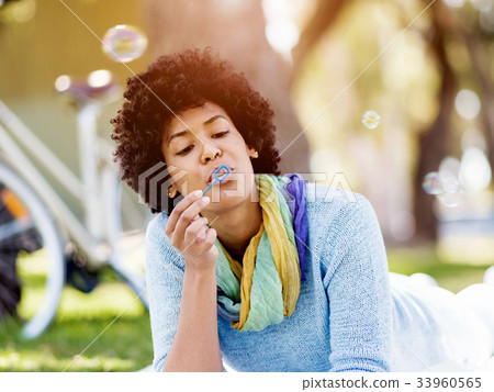 Beautiful woman blowing bubbles in park 33960565
