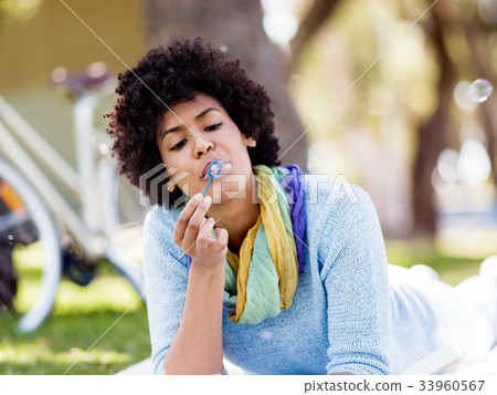 Beautiful woman blowing bubbles in park 33960567