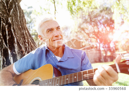 Senior man plying guitar outdoors Senior man plying guitar outdoors 33960568