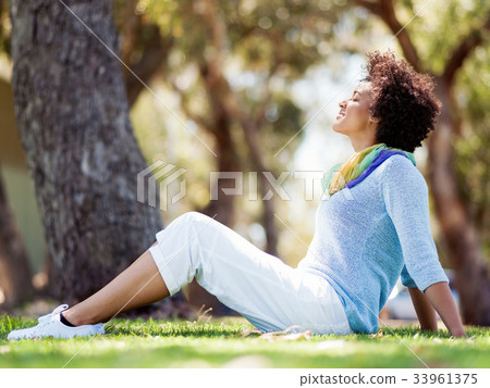 Beautiful woman sitting in summer park Beautiful woman sitting in summer park 33961375