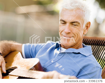 Senior man plying guitar outdoors Senior man plying guitar outdoors 33961376
