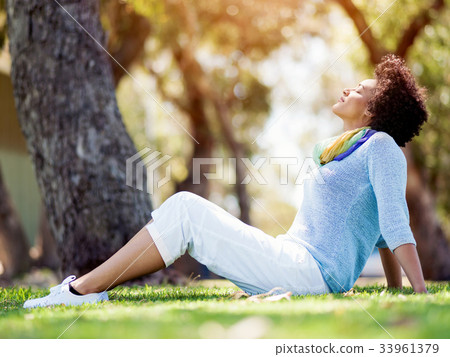 Beautiful woman sitting in summer park Beautiful woman sitting in summer park 33961379