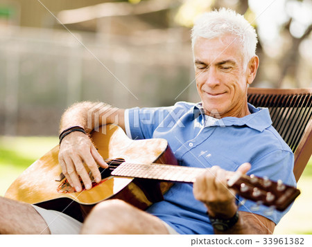Senior man plying guitar outdoors Senior man plying guitar outdoors 33961382