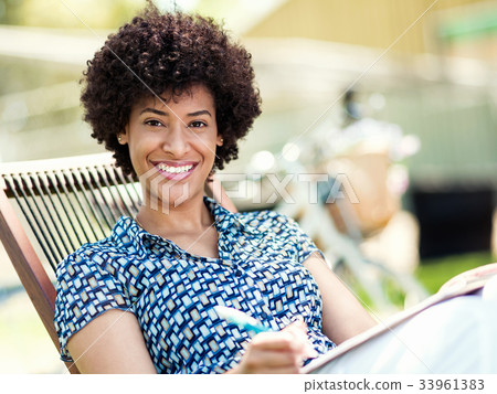 Beautiful young woman writing in her diary outdoors Beautiful young woman writing in her diary outdoors 33961383