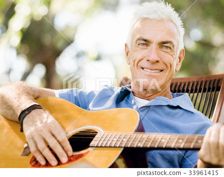 Senior man plying guitar outdoors Senior man plying guitar outdoors 33961415