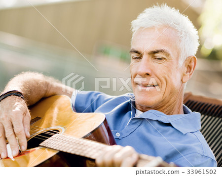 Senior man plying guitar outdoors Senior man plying guitar outdoors 33961502
