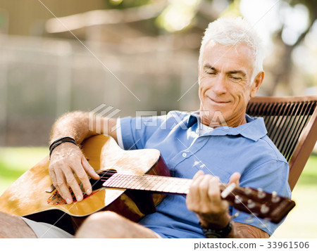 Senior man plying guitar outdoors Senior man plying guitar outdoors 33961506