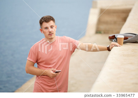 Guy listens to music and drinks coffee 33965477