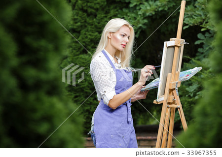 woman artist with a brush in her hand draws on 33967355