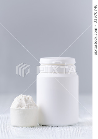 a spoon with white powder and a bottle on gray a spoon with white powder and a bottle on gray 33970746