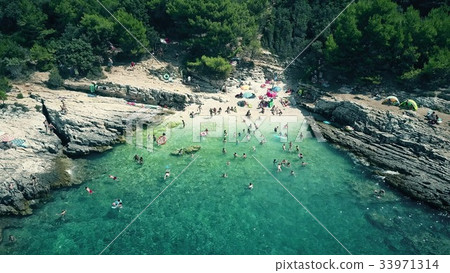 Aerial view of a small crowded rocky beach on the Aerial view of a small crowded rocky beach on the 33971314