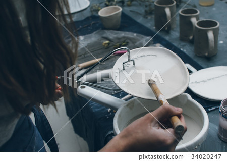 Woman with pottery tongs holding a dish 34020247
