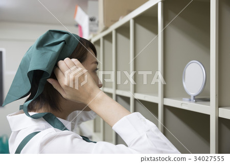 Supermarket clerk preparing in the changing room Supermarket clerk preparing in the changing room 34027555