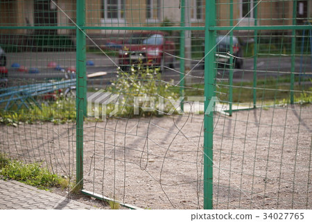 Broken mesh of metal fence of a basketball court Broken mesh of metal fence of a basketball court 34027765