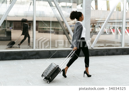 Travelling businesswoman walking with luggage  34034325
