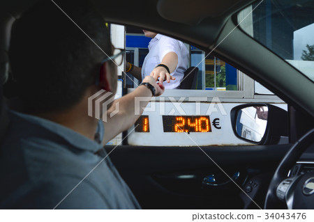A man pays money to a cashier for a toll road 34043476