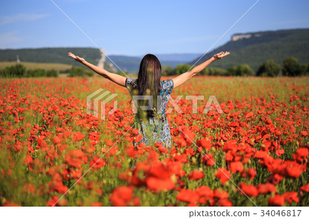 Woman stands with open arms on summer poppy field Woman stands with open arms on summer poppy field 34046817