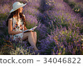 Romantic woman sits with book on lavender field 34046822