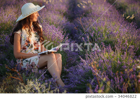 Romantic woman sits with book on lavender field Romantic woman sits with book on lavender field 34046822