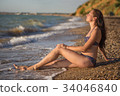 Dreamy woman sits in the sea surf 34046840