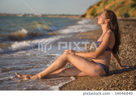 Dreamy woman sits in the sea surf Dreamy woman sits in the sea surf 34046840