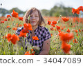 Portrait of smiling woman on poppy field 34047089