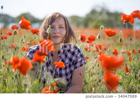 Portrait of smiling woman on poppy field Portrait of smiling woman on poppy field 34047089