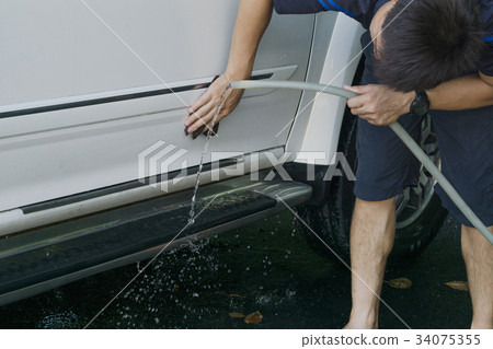 Man 's washing car by himself at home. 34075355