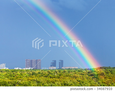 rainbow in blue rainy sky over city and urban park rainbow in blue rainy sky over city and urban park 34087910