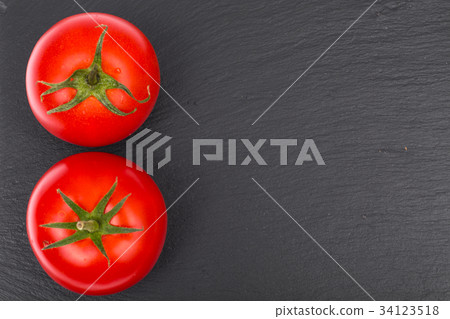 Ripe red tomatoes on black stone plate Ripe red tomatoes on black stone plate 34123518