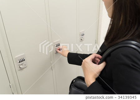 Female employee opening locker Female employee opening locker 34139345