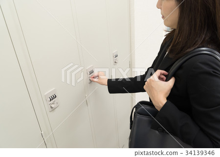 Female employee opening locker Female employee opening locker 34139346