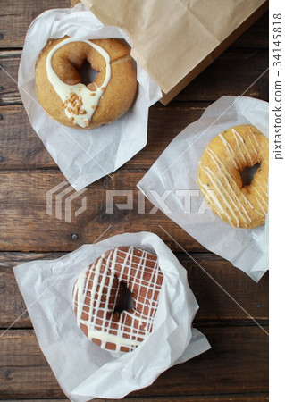 Three types of fluffy donuts in wrappers Three types of fluffy donuts in wrappers 34145818