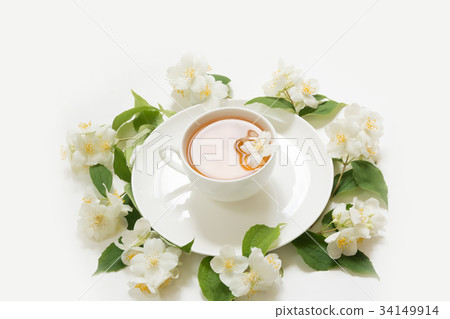 Jasmine leaves and flowers around cup of tea. 34149914
