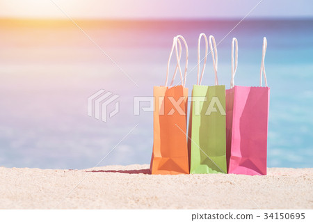 Shopping bags on sand against caribbean sea water Shopping bags on sand against caribbean sea water 34150695