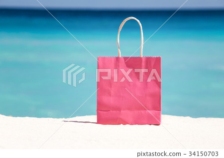 Shopping bag on sand against caribbean sea water 34150703