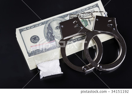 Handcuffs on stack of dollar banknotes and cocaine Handcuffs on stack of dollar banknotes and cocaine 34151192