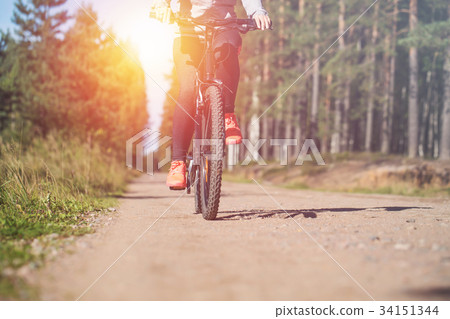 Woman riding a mountain bicycle along path Woman riding a mountain bicycle along path 34151344