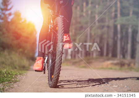 Woman riding a mountain bicycle along path Woman riding a mountain bicycle along path 34151345