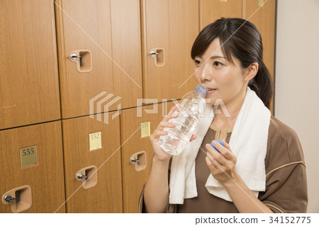 Woman doing hydration in the changing room of the spa facility 34152775